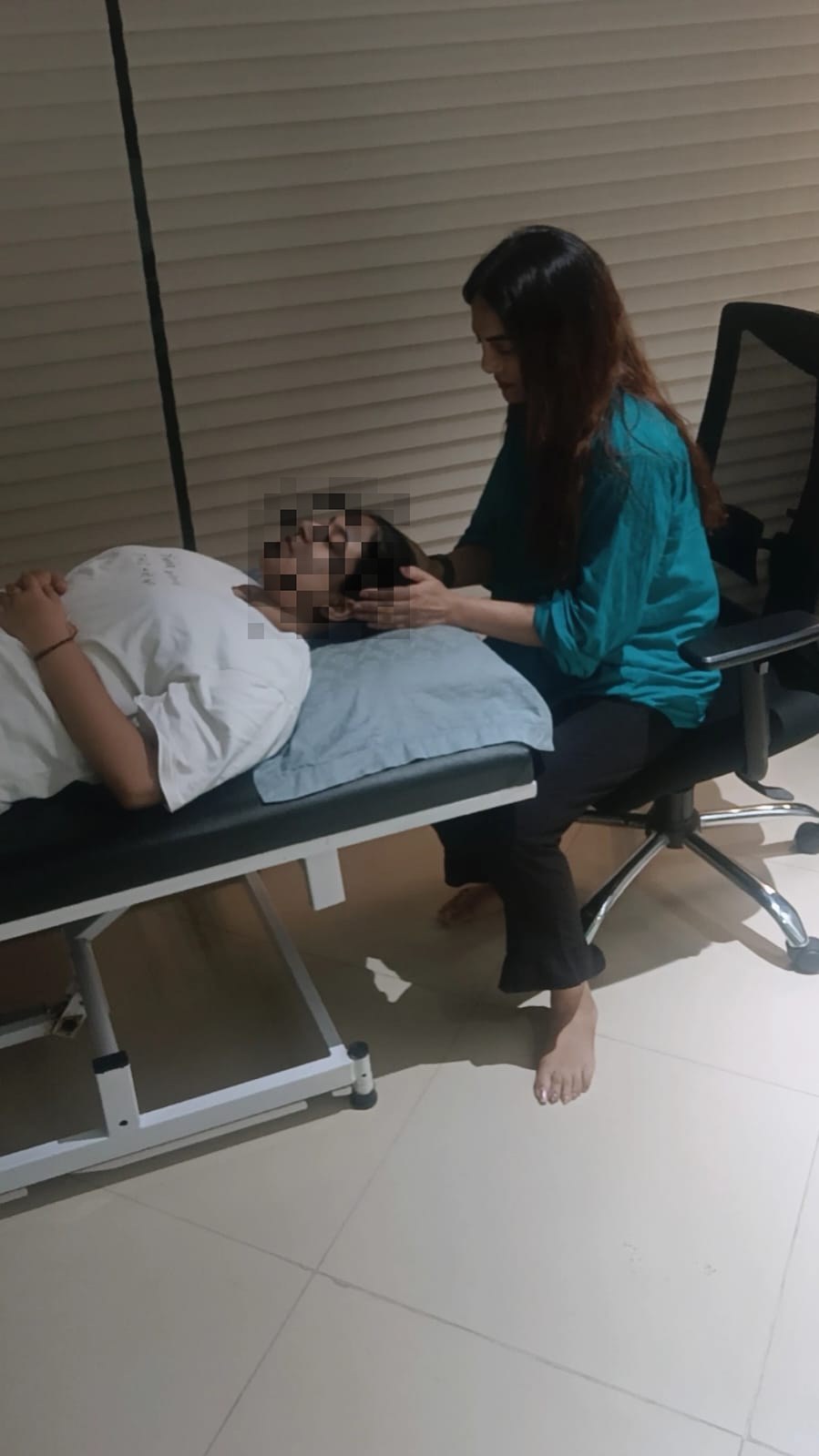 Vibha Jain seated beside a client resting on a therapy couch during a guided relaxation session in Mumbai