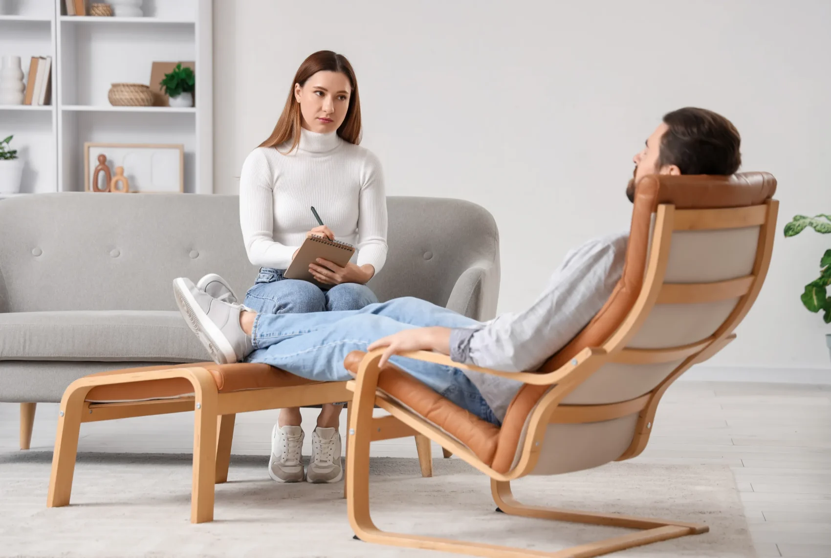 A practitioner listening and taking notes while a client sits comfortably at the beginning of a regression therapy session